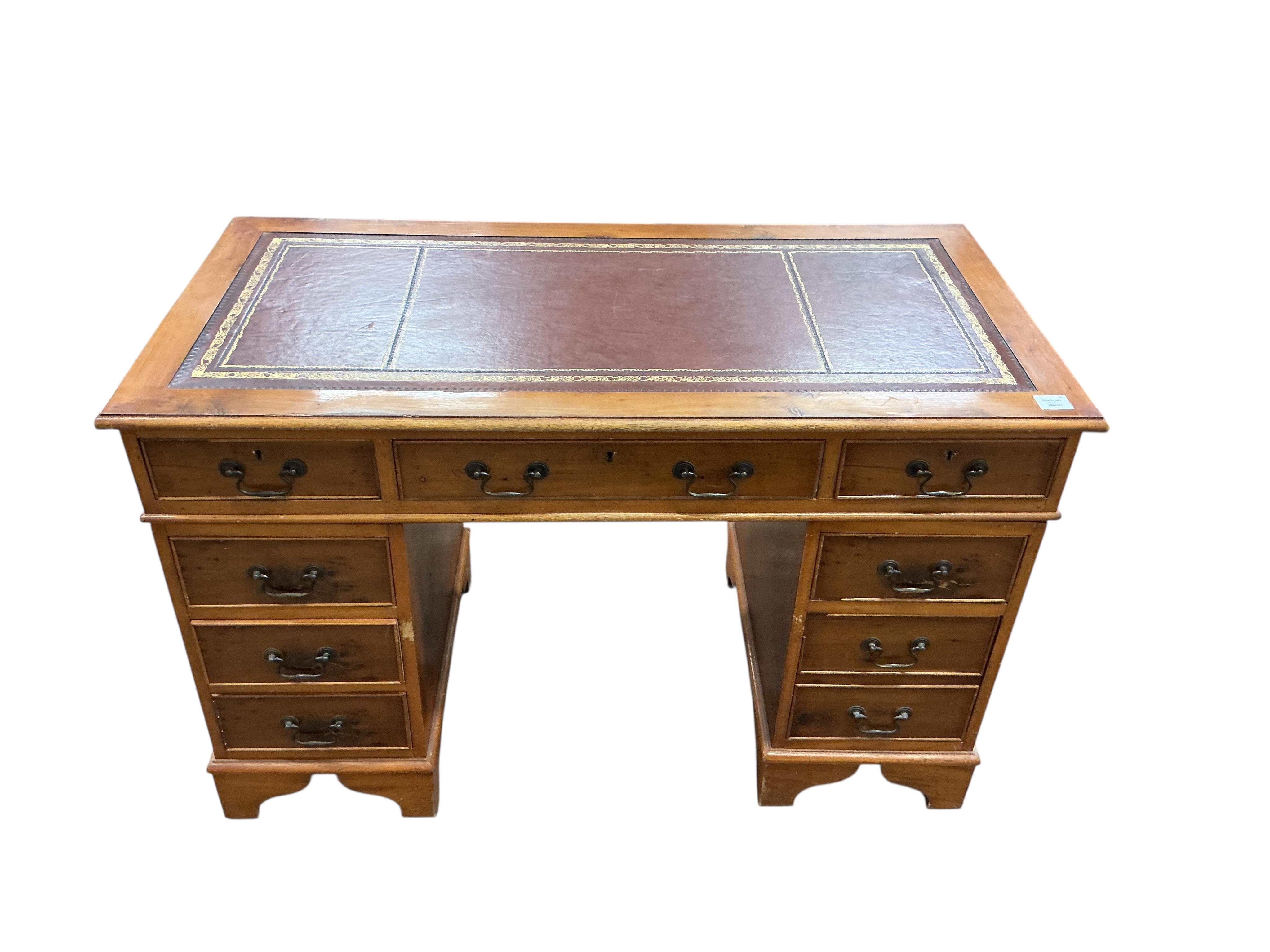 A reproduction yew pedestal desk, width 132cm, depth 61cm, height 77cm and a buttoned burgundy leather swivel desk chair